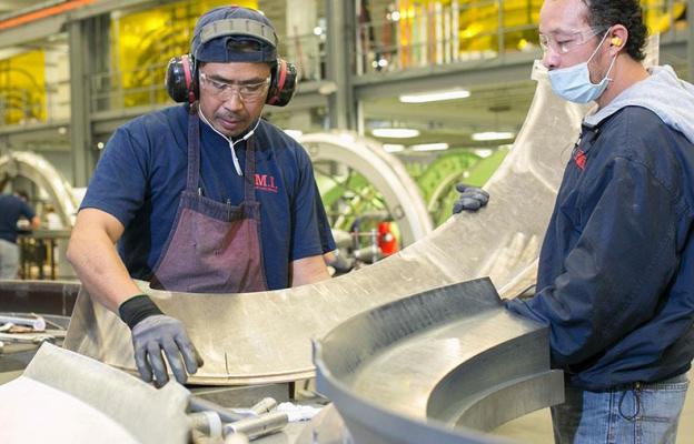 Two men working on large metal parts